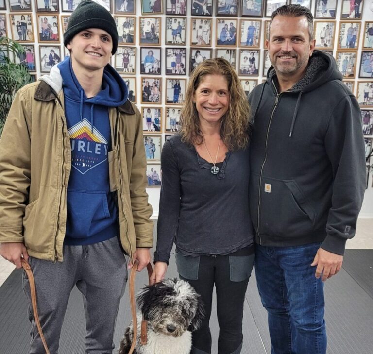 a man and a woman standing next to a dog