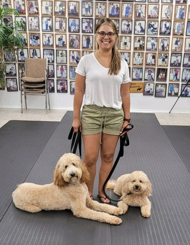 a woman standing next to two dogs on a mat