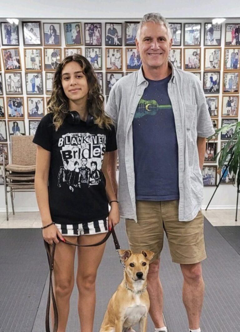 a man and woman standing next to a dog on a leash