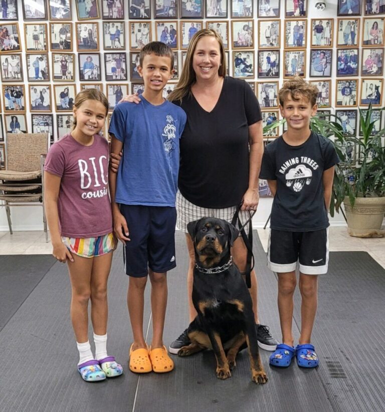 a woman standing with two boys and a dog