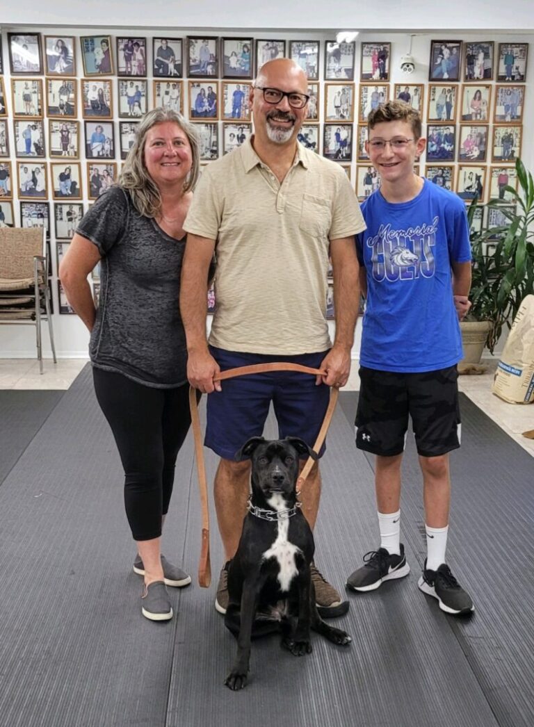 a man and two women standing with a dog on a leash
