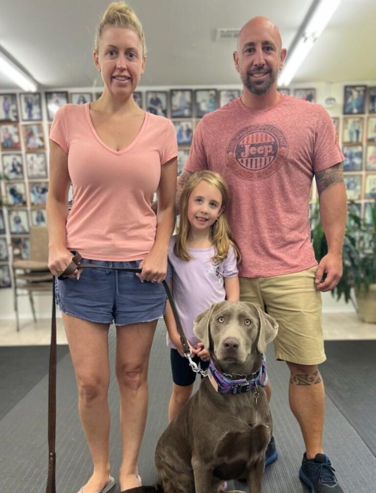 a man, woman and child standing next to a dog