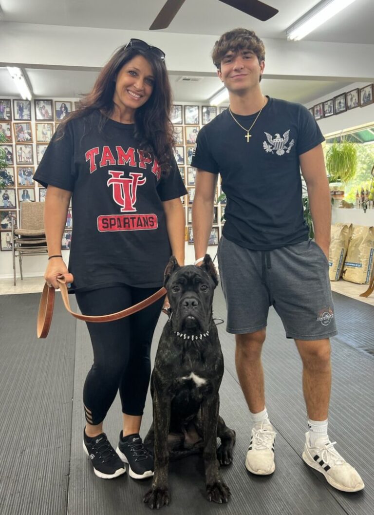a man and a woman standing next to a dog