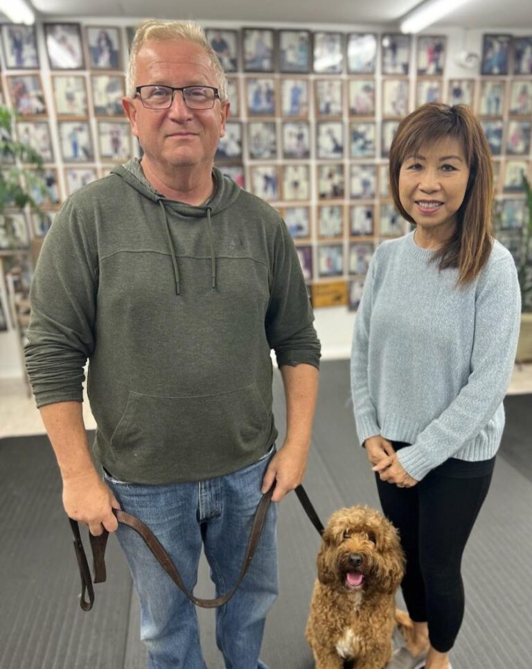 a man and a woman standing with a dog
