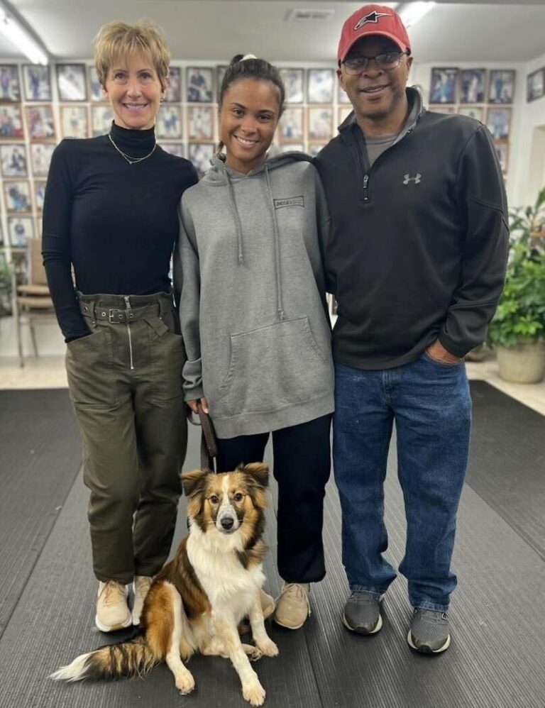 three people and a dog posing for a picture