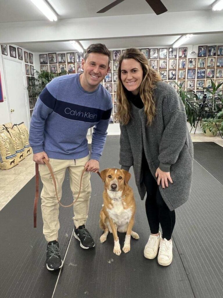 a man and a woman standing next to a dog