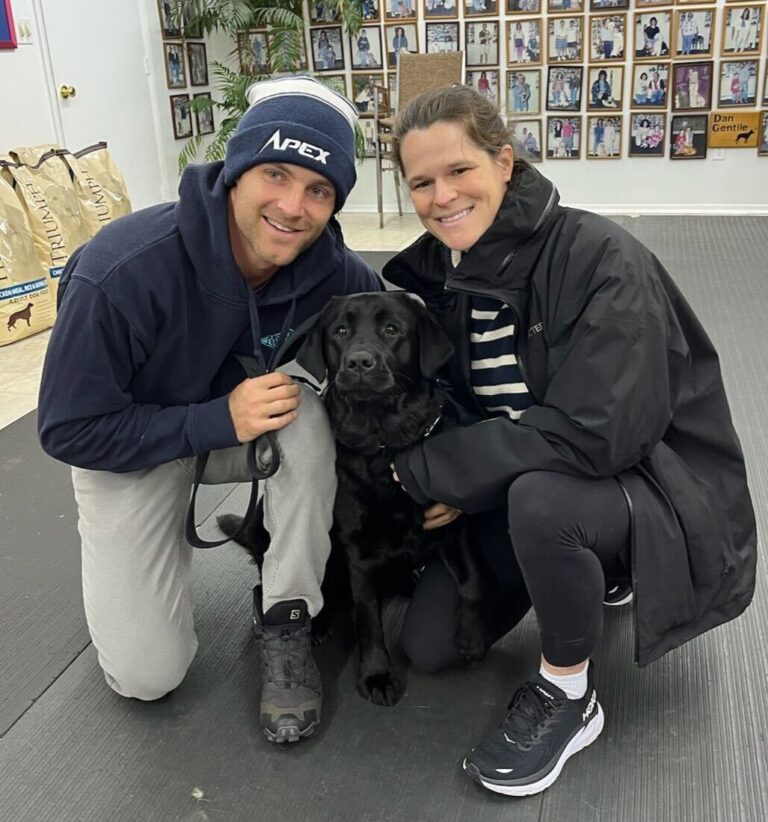 a man and a woman pose with a dog