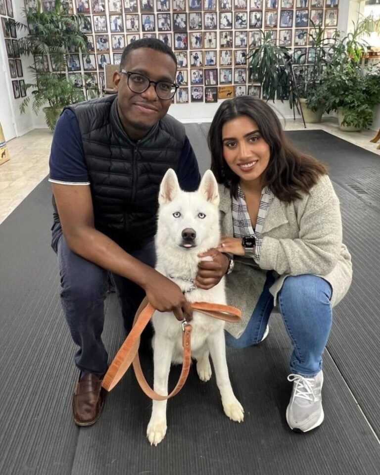 a man and a woman pose with a dog