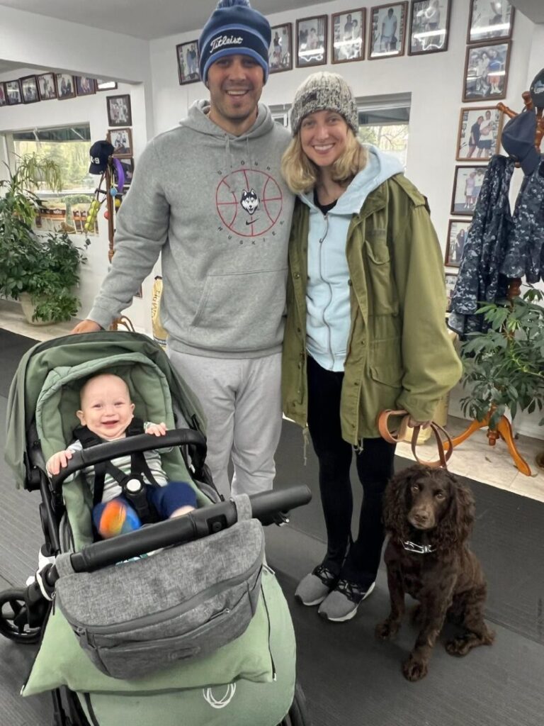 a man and woman standing next to a baby in a stroller