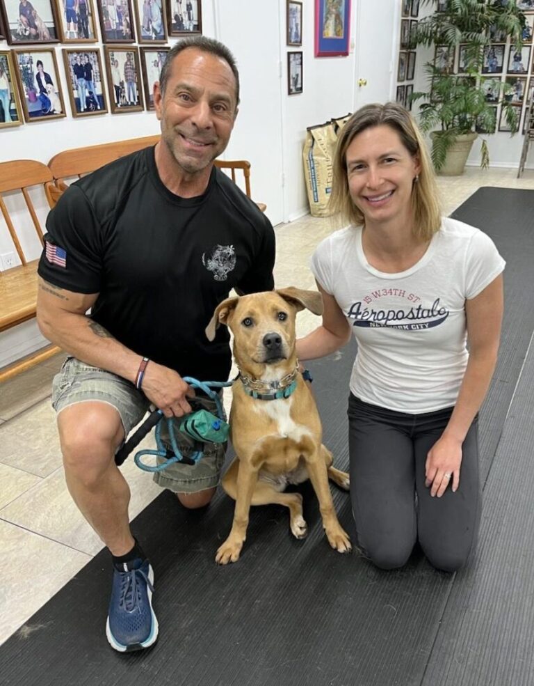 a man and a woman pose with a dog