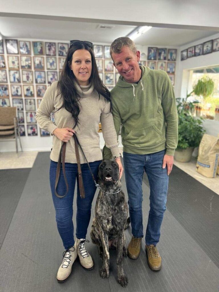 a man and a woman standing next to a dog