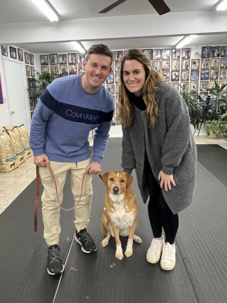 a man and a woman standing next to a dog