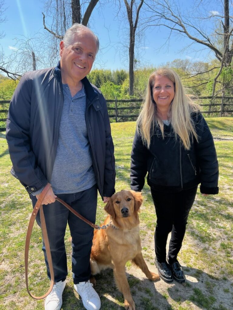 a man and a woman standing next to a brown dog
