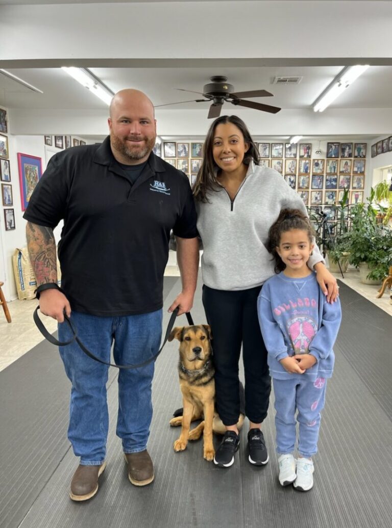 a man, woman, and child posing for a picture with a dog