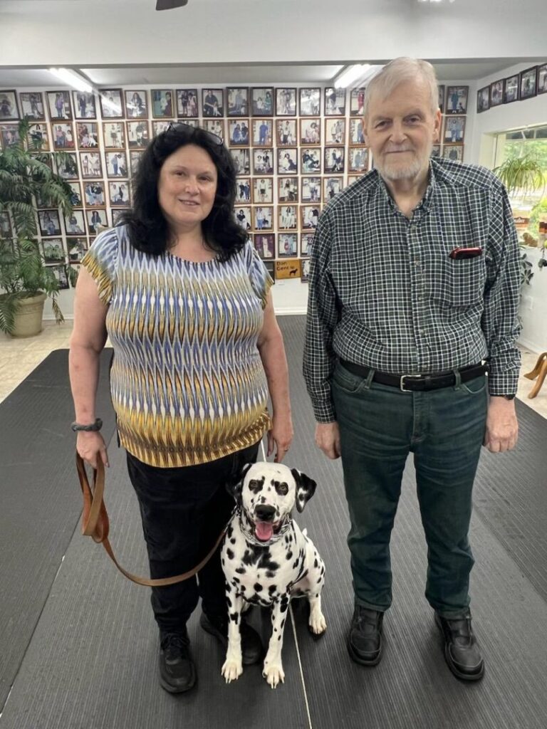 a man and woman standing next to a dog on a leash