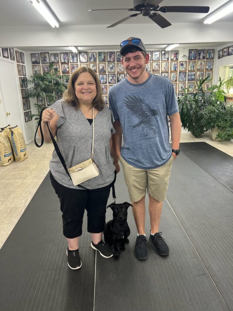 a man and a woman pose for a picture with a dog