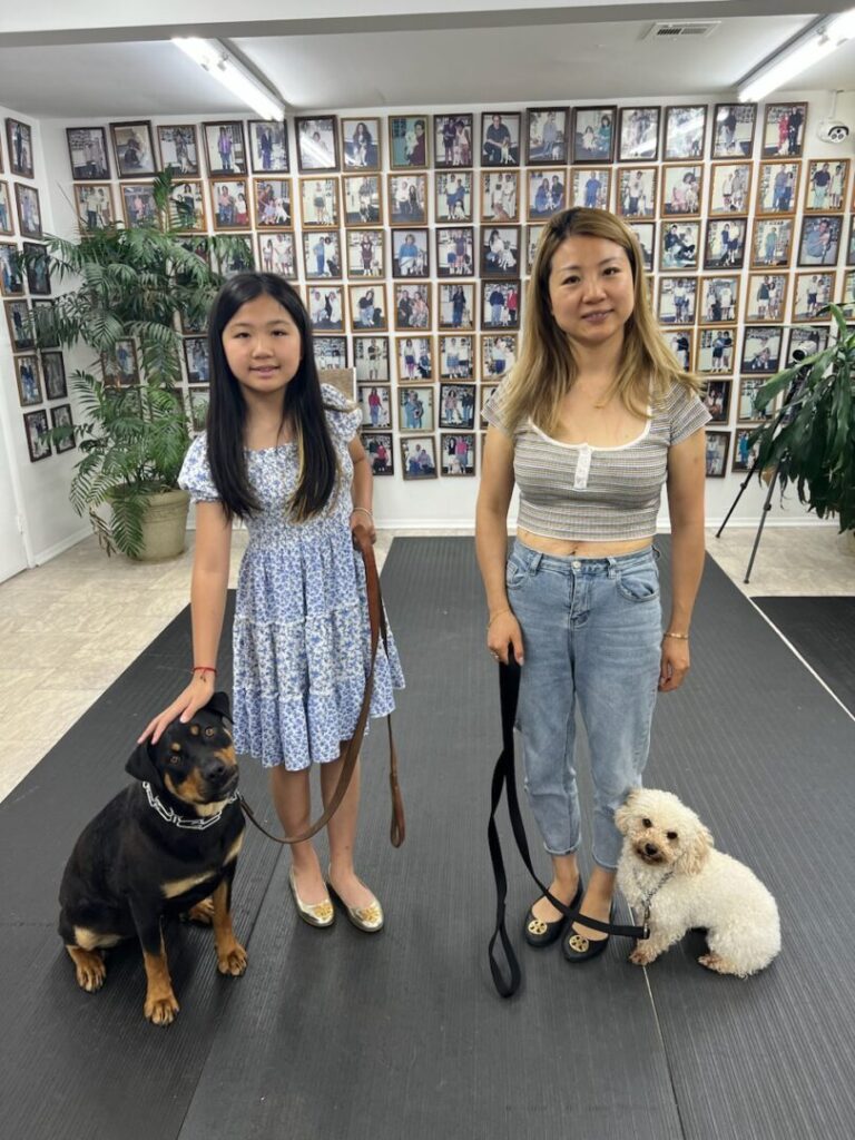 two women standing next to each other with two dogs on leashes