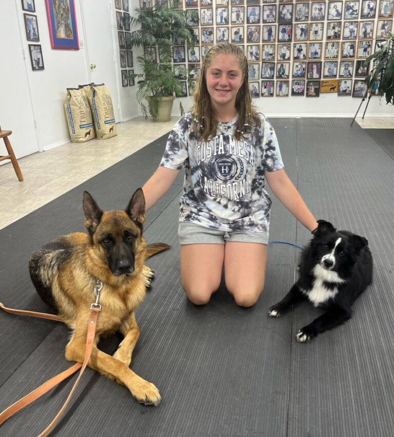 a woman sitting on a mat with two dogs