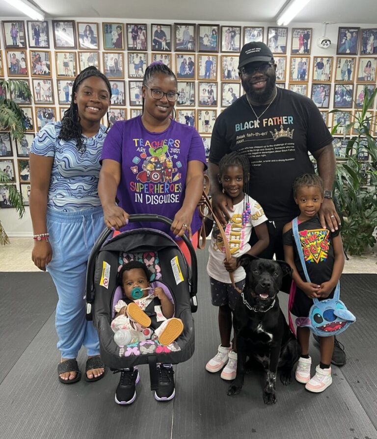 a group of people standing next to a black dog