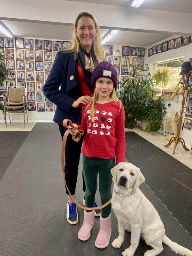 a woman standing next to a little girl on a leash