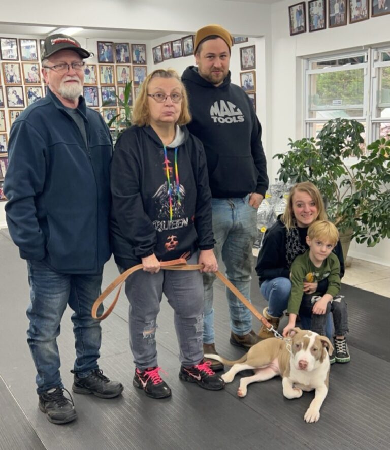 a group of people standing around a dog on a leash