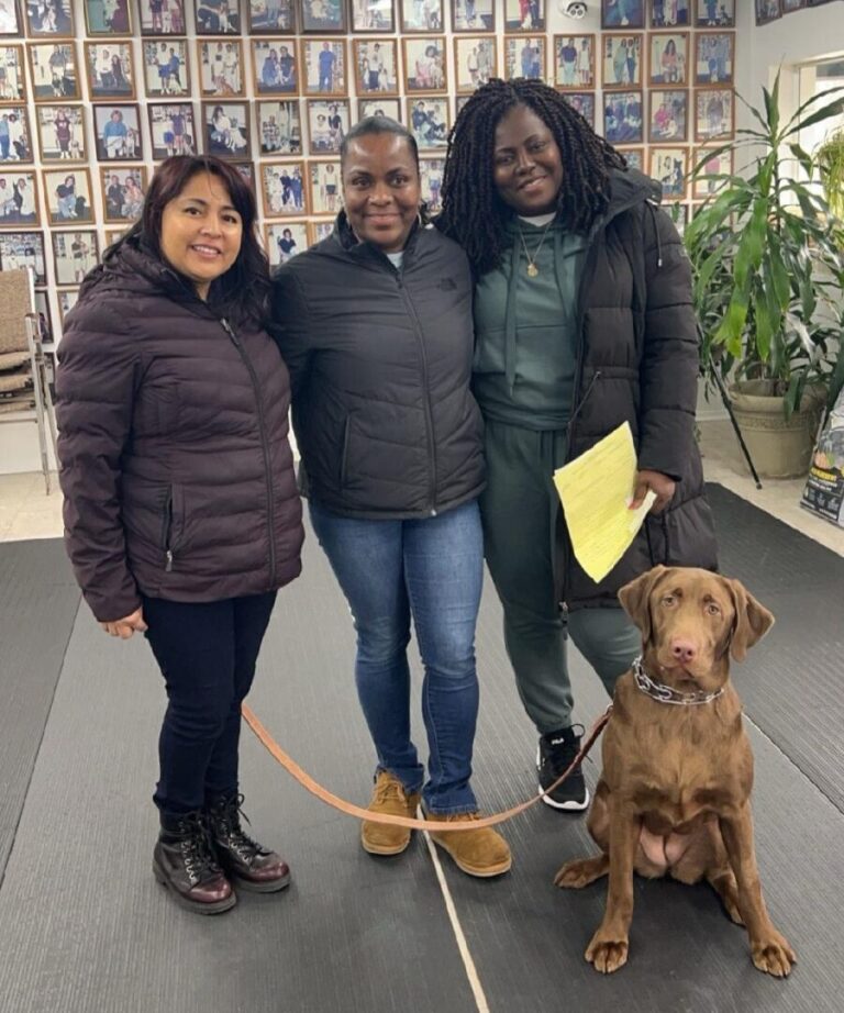 a group of three women standing next to a brown dog