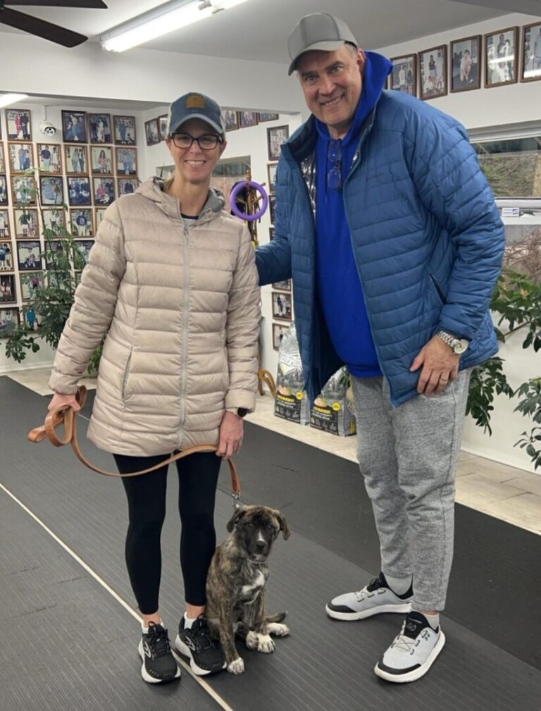 a man and a woman standing next to a dog