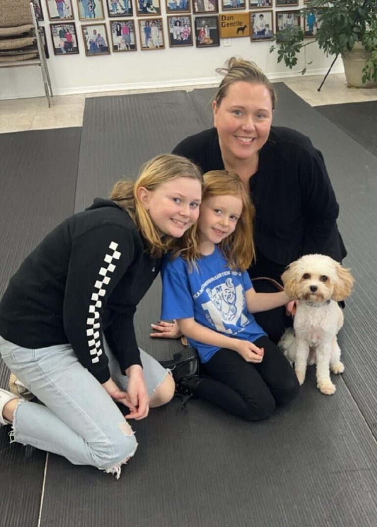 a woman and two girls are sitting on a mat with a dog