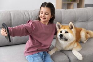 a little girl sitting on a couch next to a dog