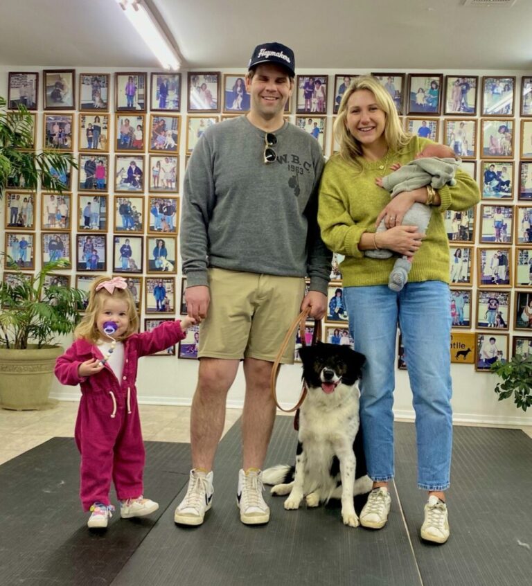 a man, woman, and child standing on a mat with a dog