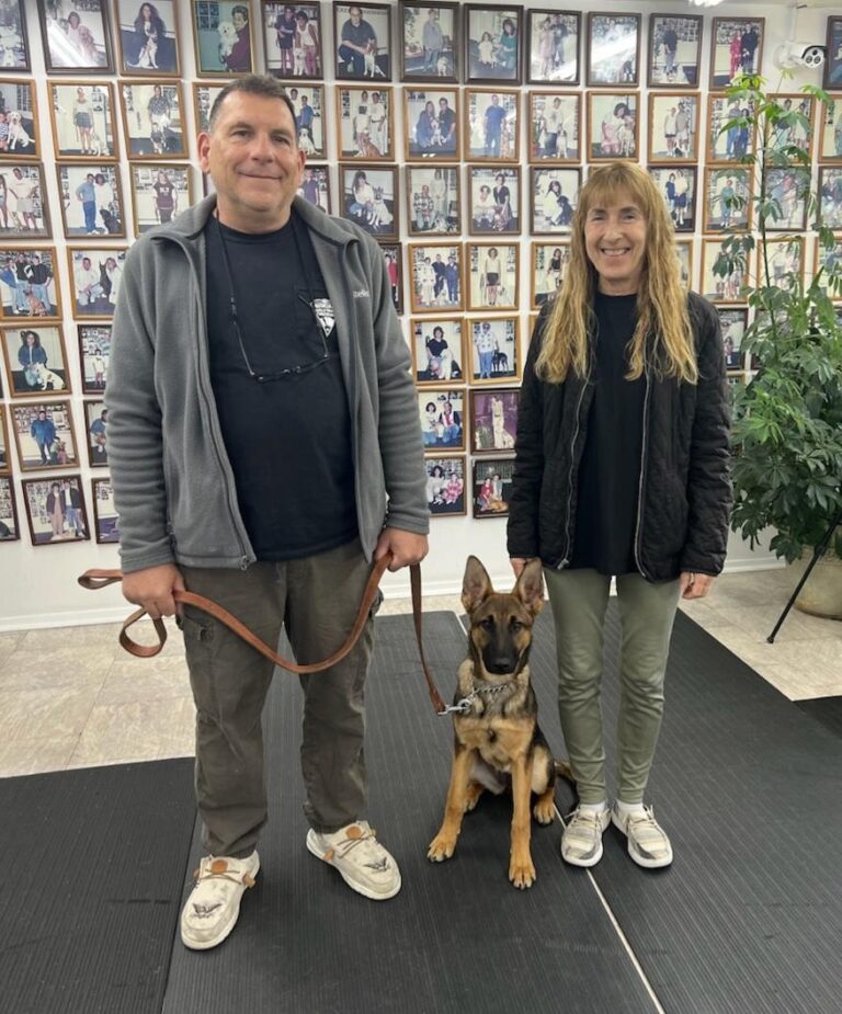 a man and a woman standing next to a dog