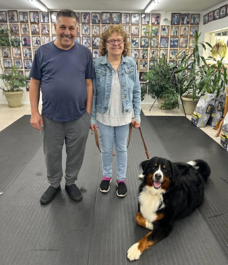 a man and a woman standing next to a dog on a leash
