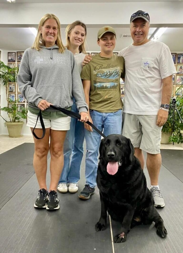 a group of people standing next to a black dog