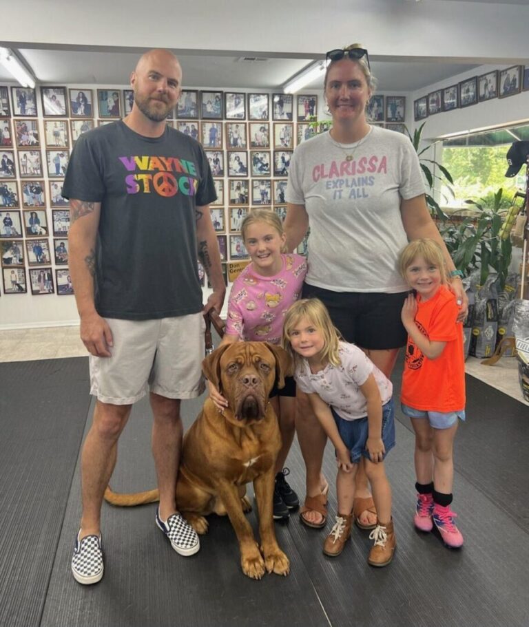 a group of people standing next to a brown dog