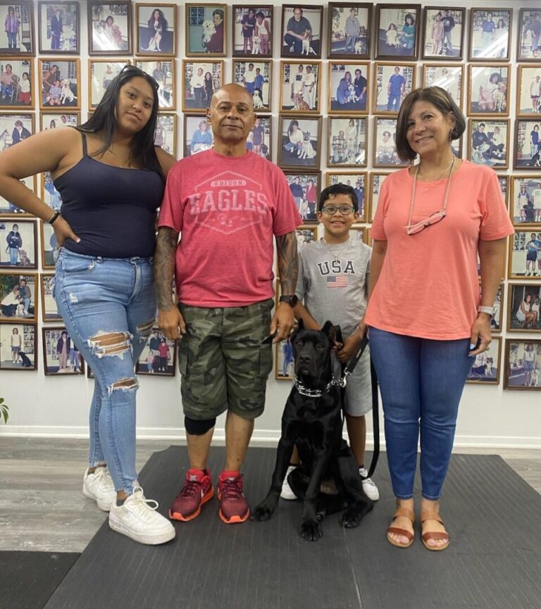 a group of people standing next to a black dog