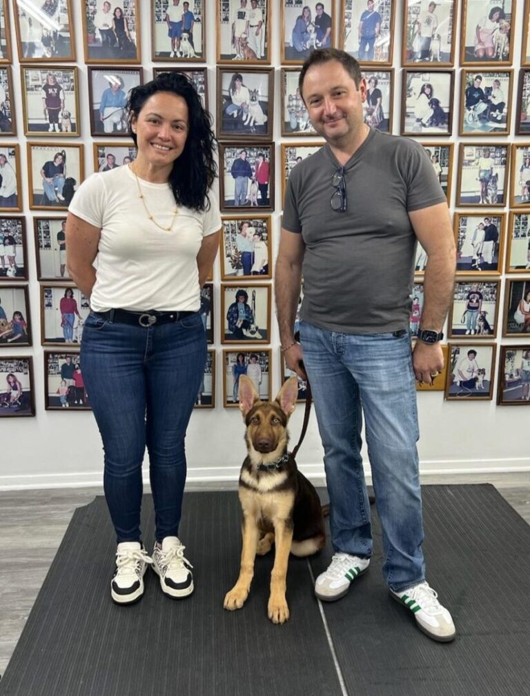 a man and a woman standing next to a dog