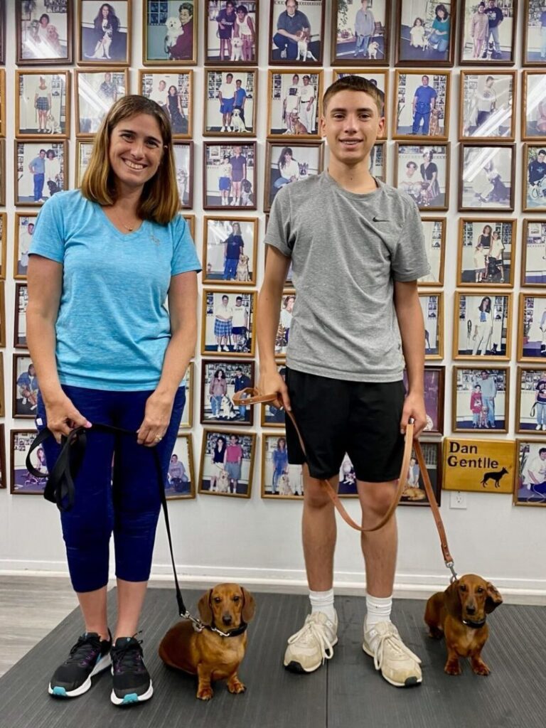 a man and a woman standing next to two dogs