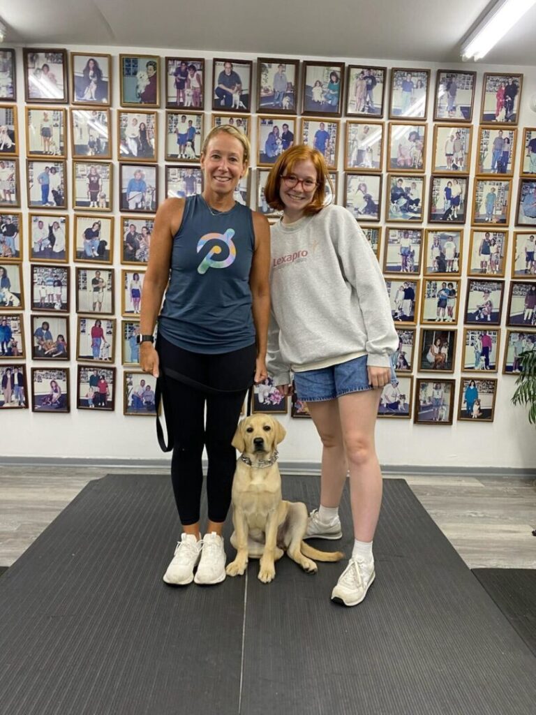 a couple of women standing next to a dog