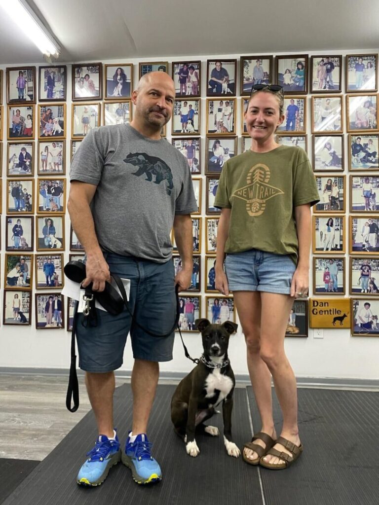 a man and a woman standing next to a dog