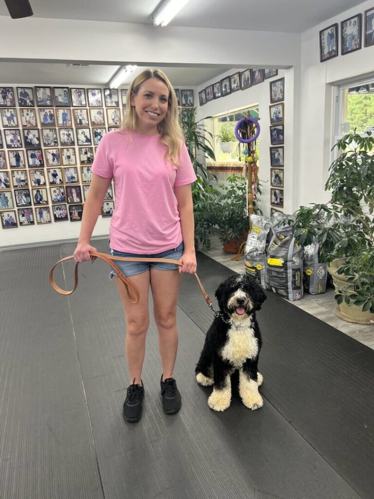 a woman in a pink shirt is holding a black and white dog on a leash