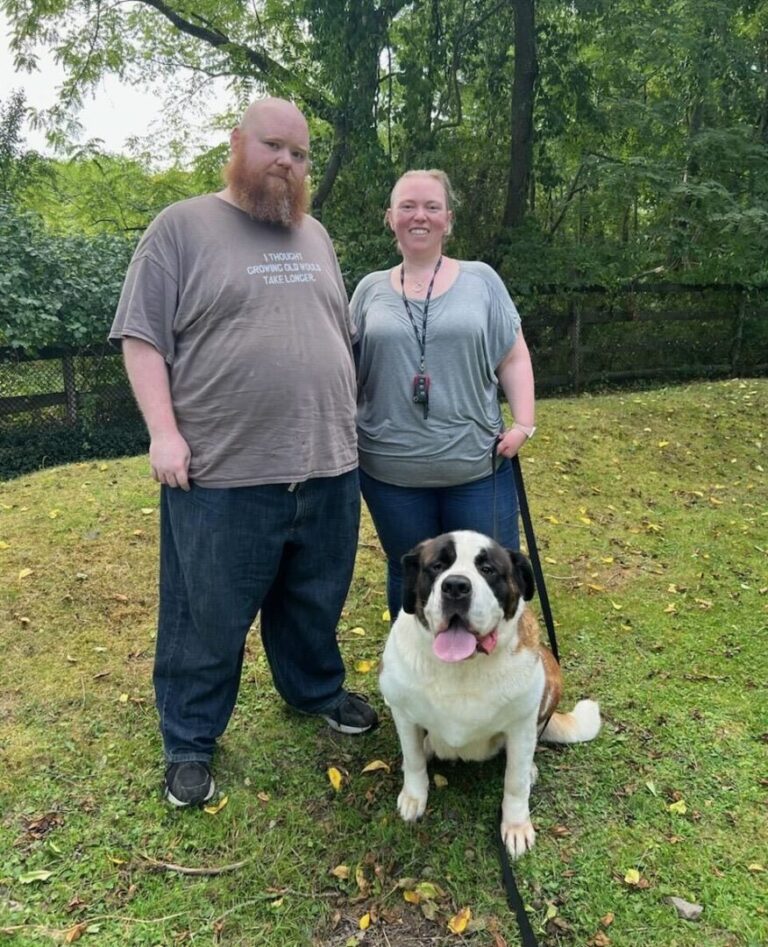 a man and a woman standing next to a dog