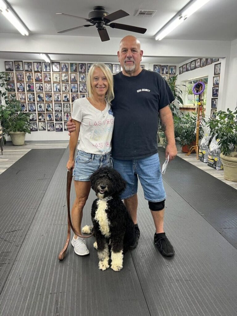 a man and woman standing next to a black and white dog