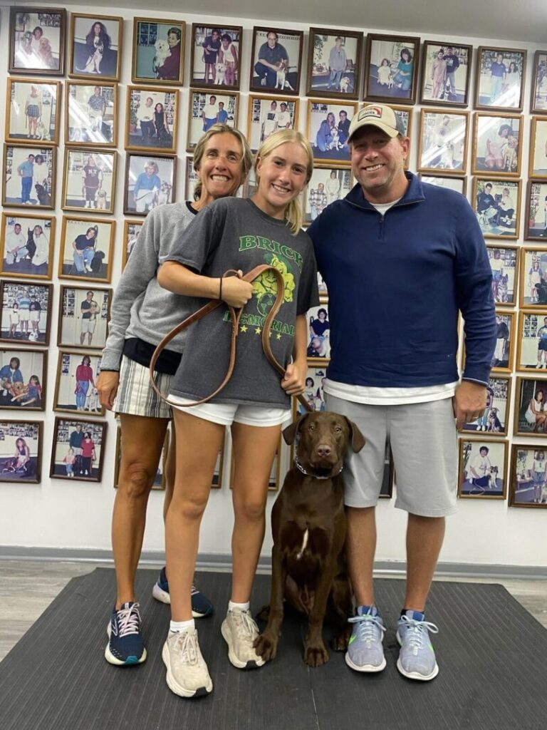 a man and two women standing next to a dog