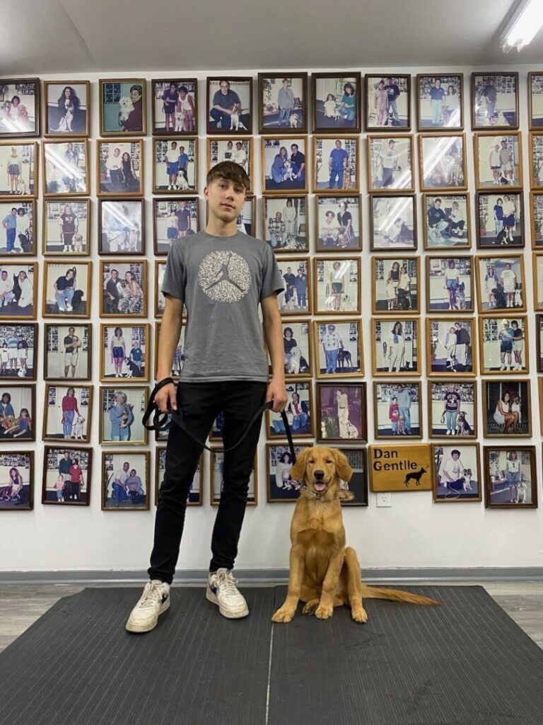 a man standing next to a brown dog on top of a black mat
