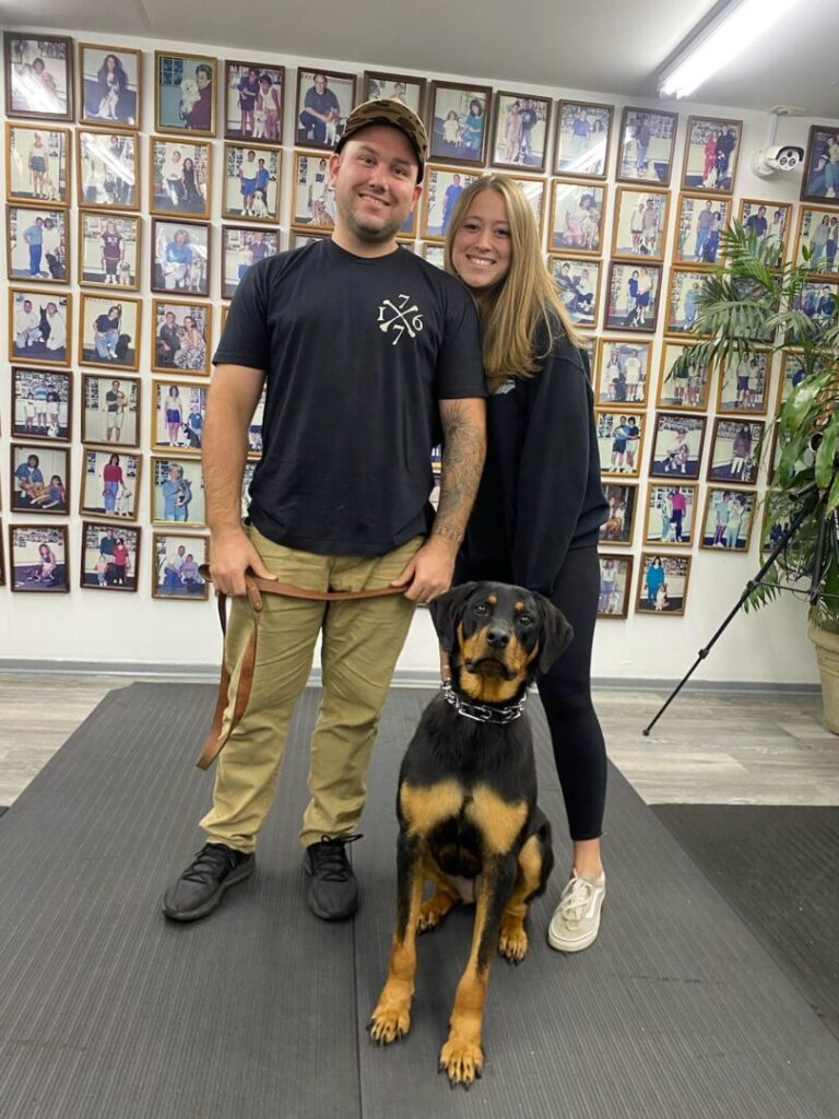 a man and a woman standing next to a dog