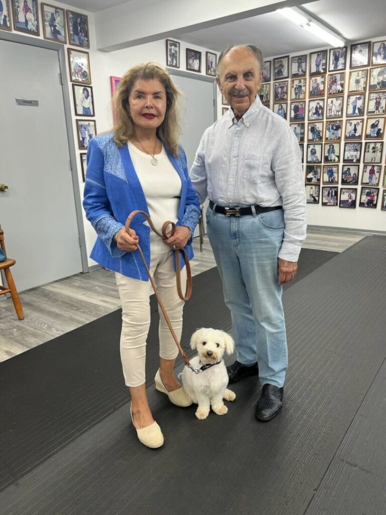 a man and woman standing next to a white dog