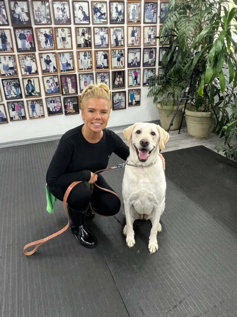 a woman kneeling down next to a white dog