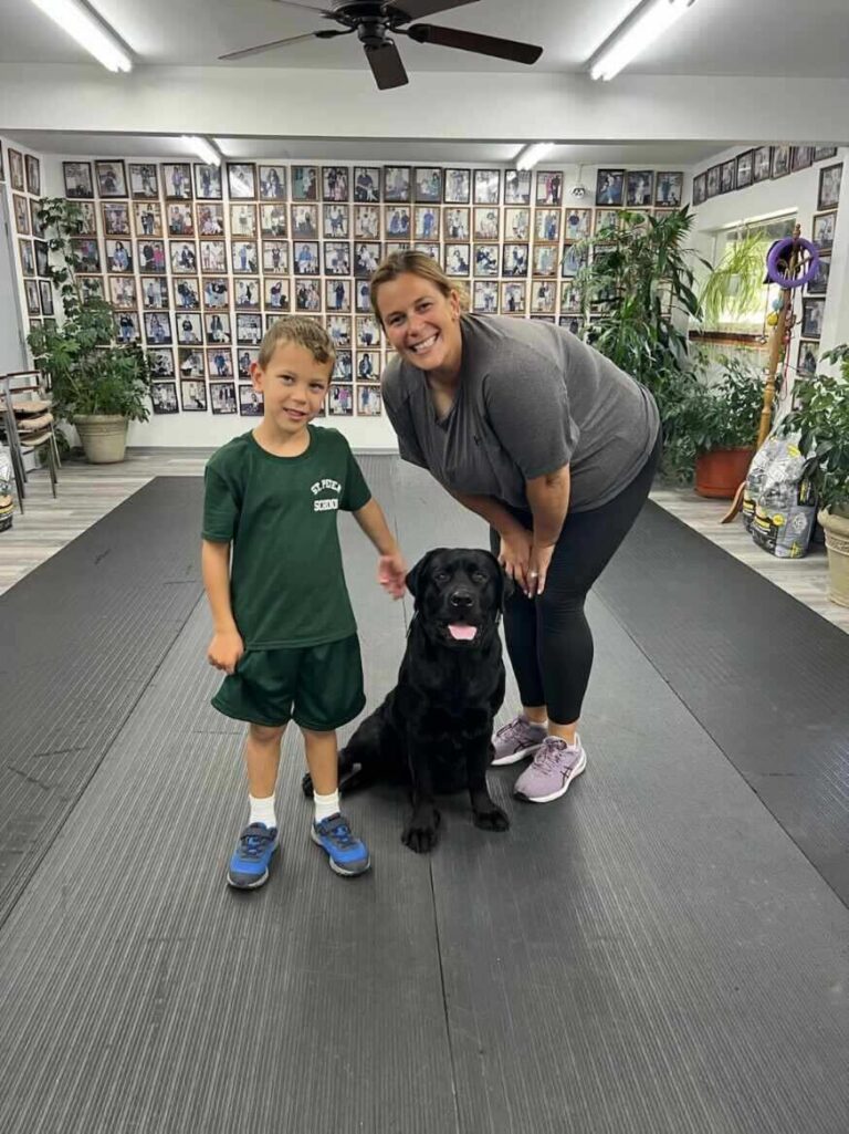 a woman standing next to a child and a black dog