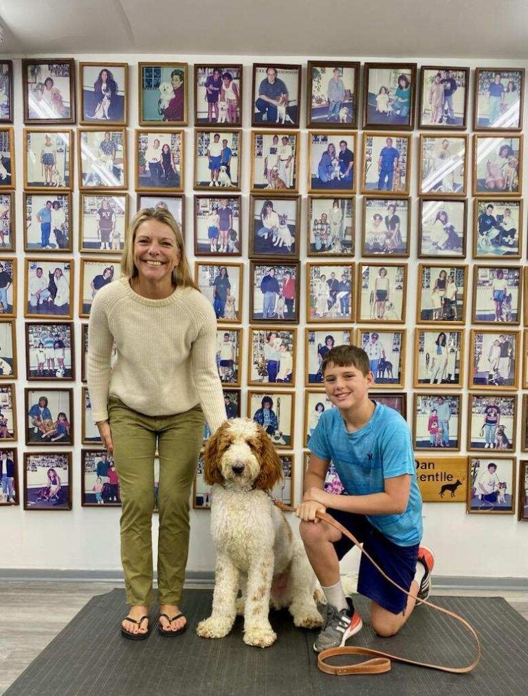 a woman and boy standing in front of a wall of pictures