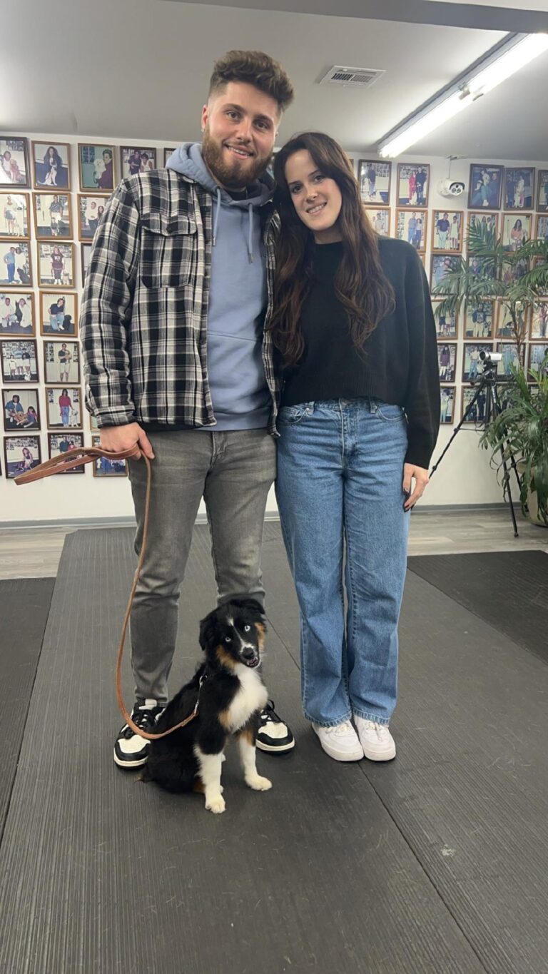 a man and woman standing next to a dog